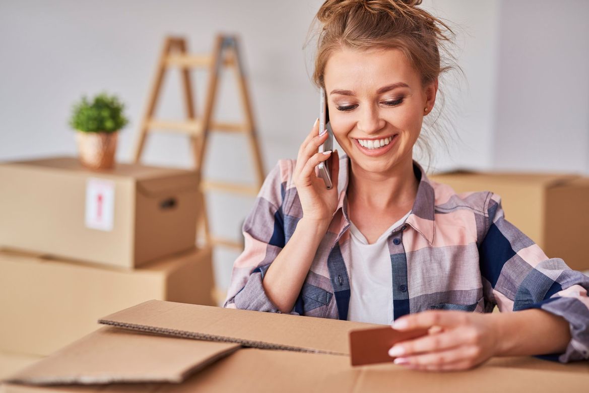 A woman is sitting at a table talking on a cell phone while holding a credit card.