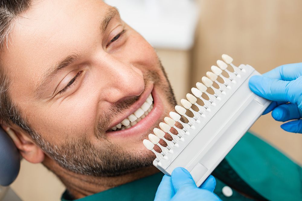 A Man Is Sitting In A Dental Chair While A Dentist Examines His Teeth — Mittagong Dental Care In Mittagong, NSW