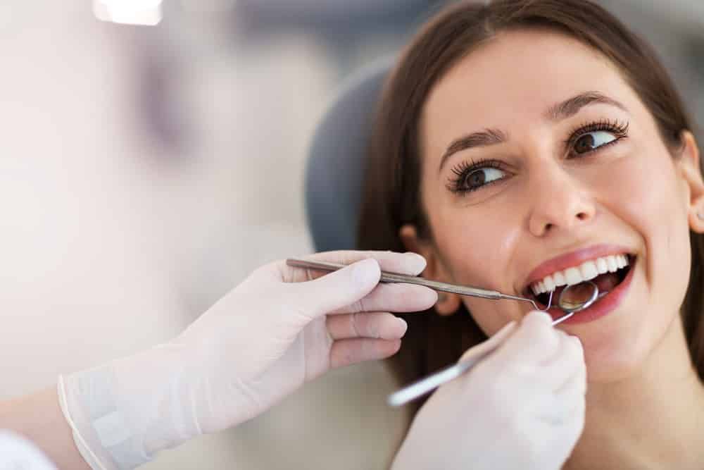 A Woman Is Getting Her Teeth Examined By A Dentist — Mittagong Dental Care In Mittagong, NSW