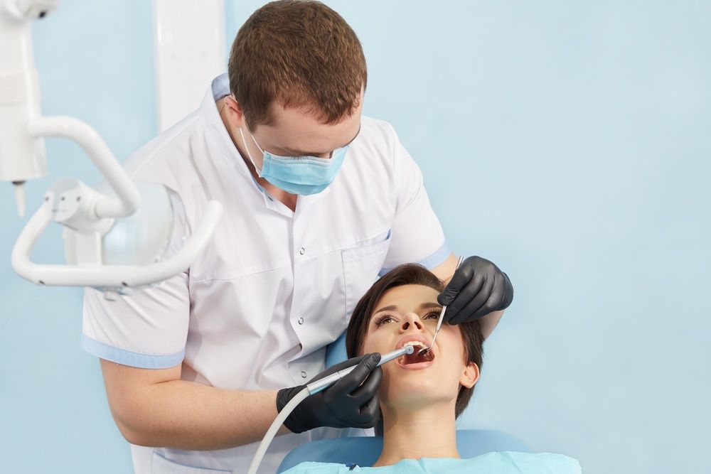 A Dentist is Examining a Woman 's Teeth in a Dental Office — Mittagong Dental Care In Mittagong, NSW
