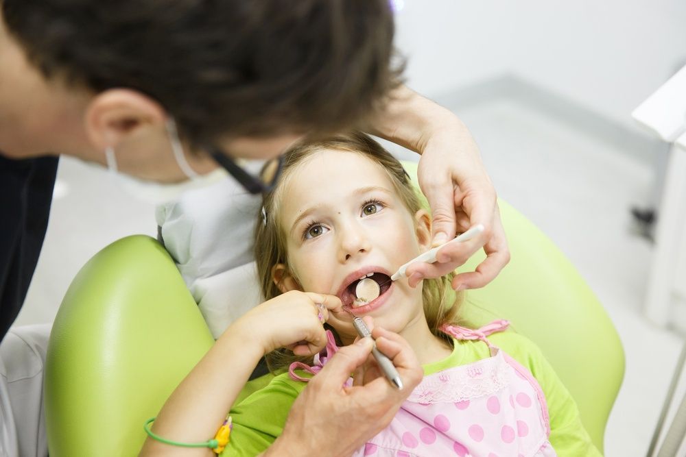 A Little Girl is Sitting in a Dental Chair Getting Her Teeth Examined — Mittagong Dental Care In Mittagong, NSW