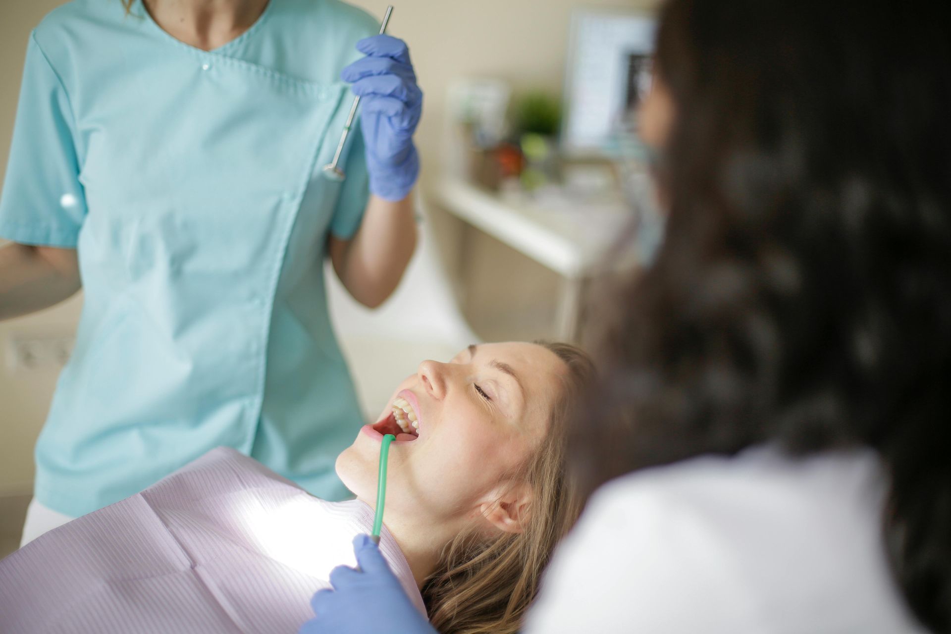 A Woman Is Sitting In A Dental Chair While A Dentist Examines Her Teeth — Mittagong Dental Care In Mittagong, NSW