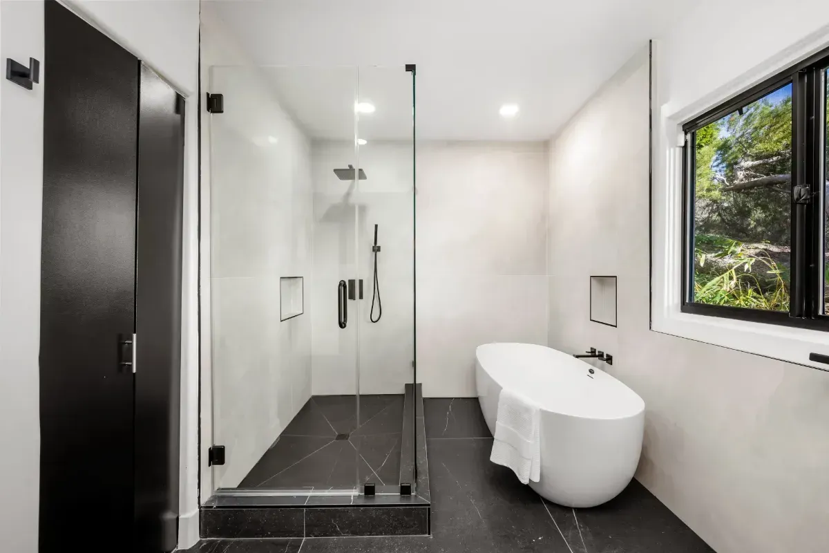 Modern bathroom with black shower, white freestanding tub, and large window - Redlands CA Kearney Restorations