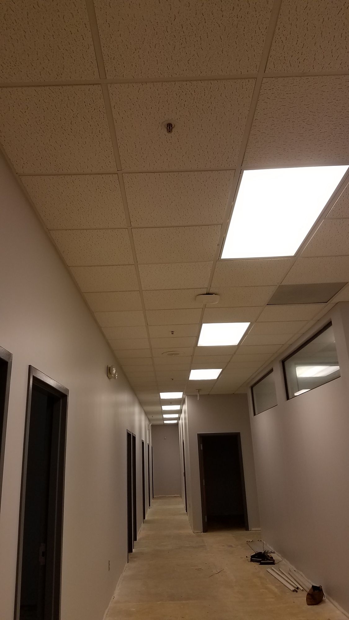 A long hallway with a tiled ceiling and lights on the ceiling.