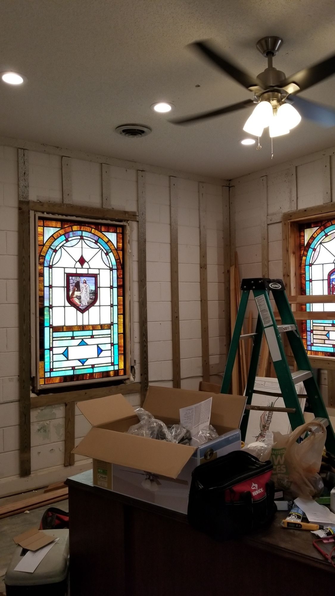 A room with stained glass windows and a ceiling fan.