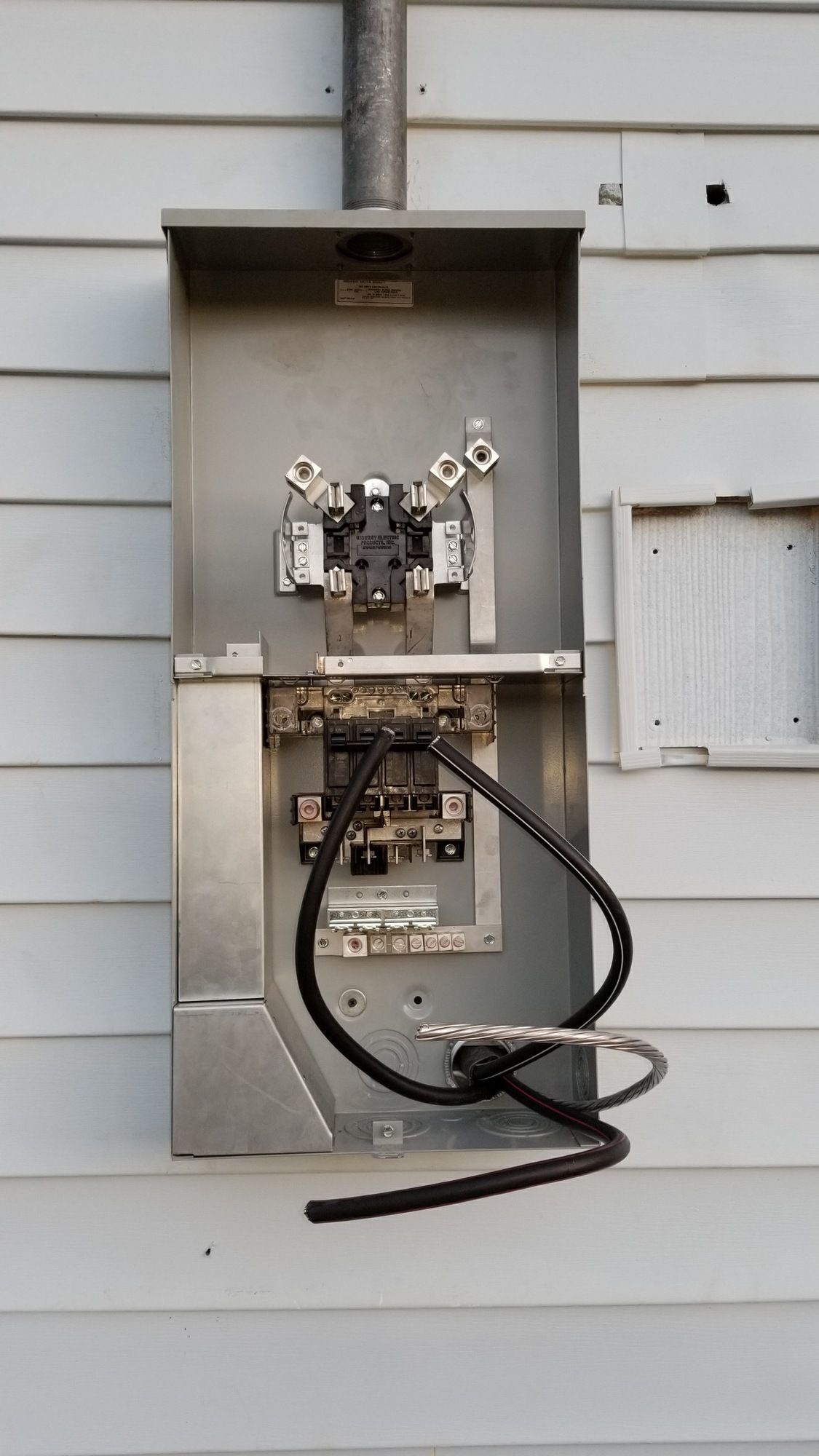 An electrical box is attached to the side of a house.