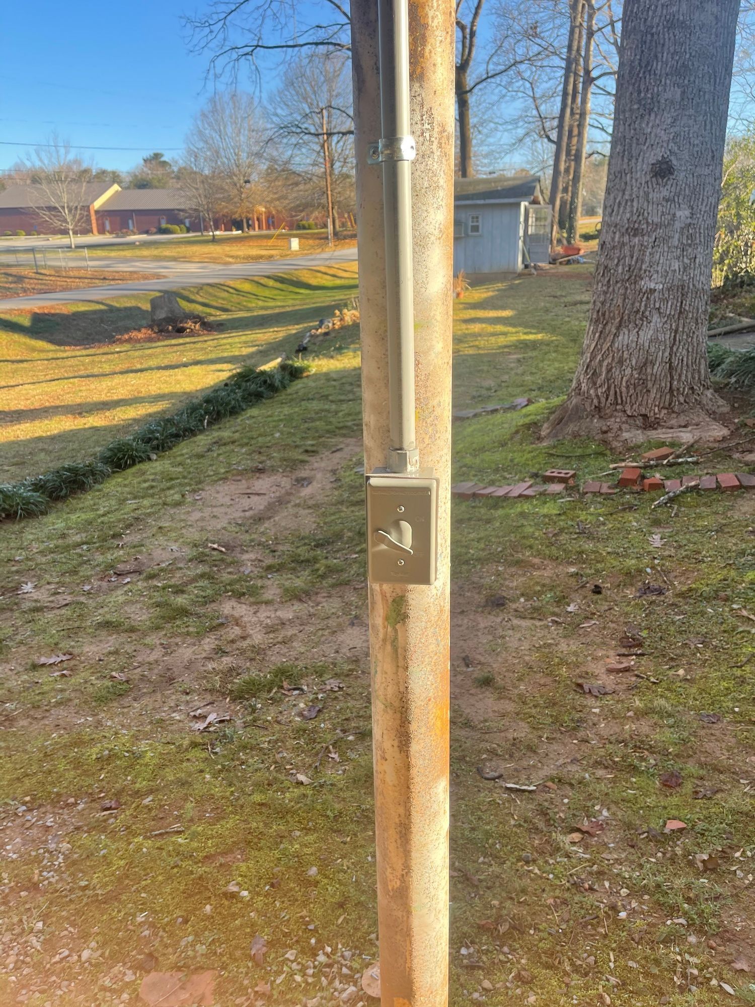 A wooden pole with a electrical box attached to it.