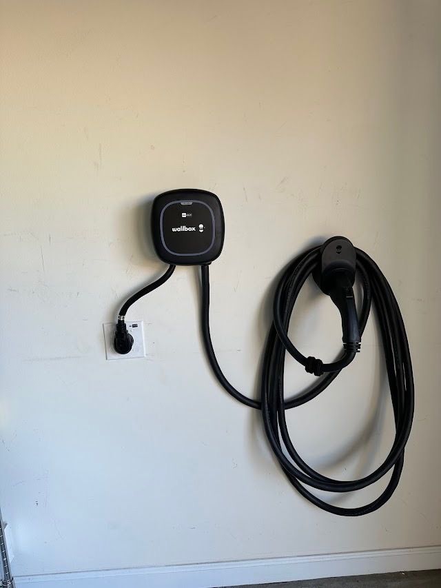An electric car charger is attached to a wall.