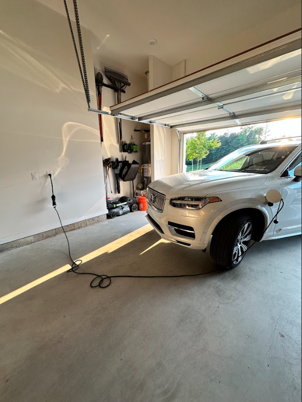 A white car is parked in a garage with the door open.