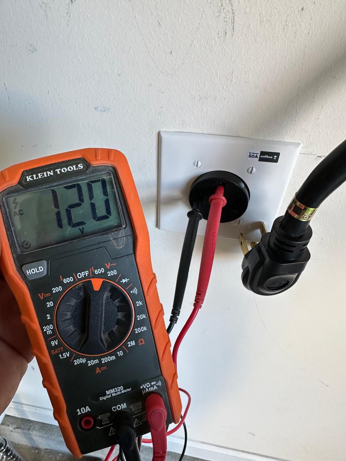 A digital multimeter is plugged into an electrical outlet.