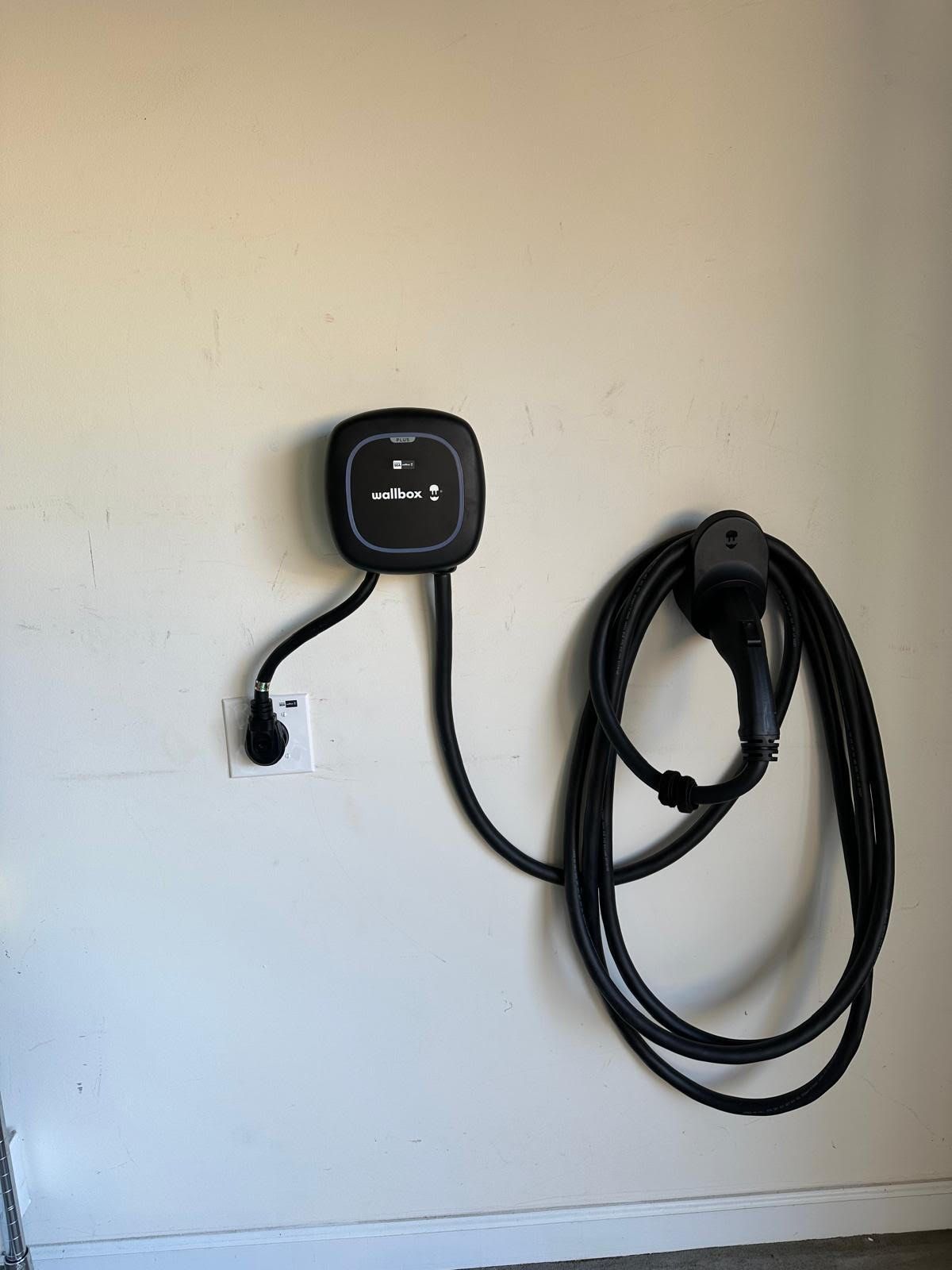 An electric car charger is attached to a wall.