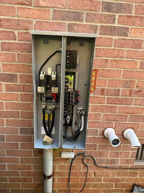 A brick wall with a electrical box attached to it.