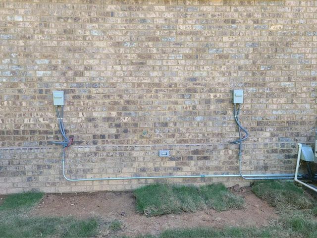 There are two electrical outlets on the side of a brick wall.