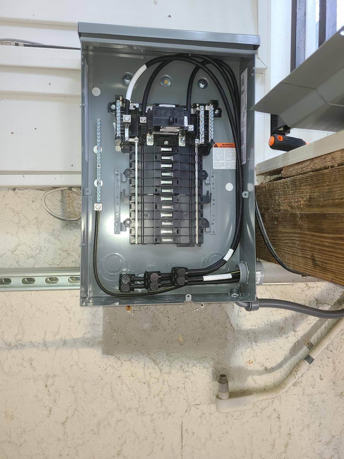 A electrical box is hanging on a wall next to a window.