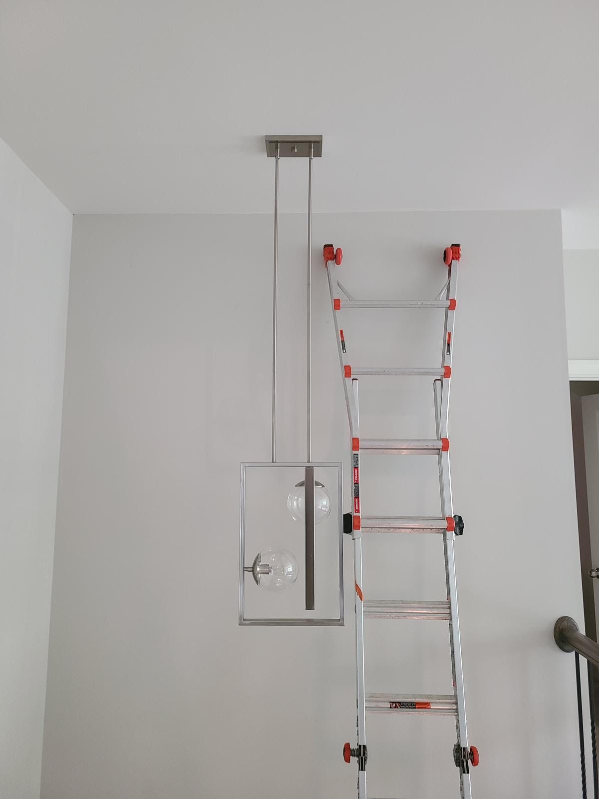 A ladder is hanging from the ceiling next to a light fixture.