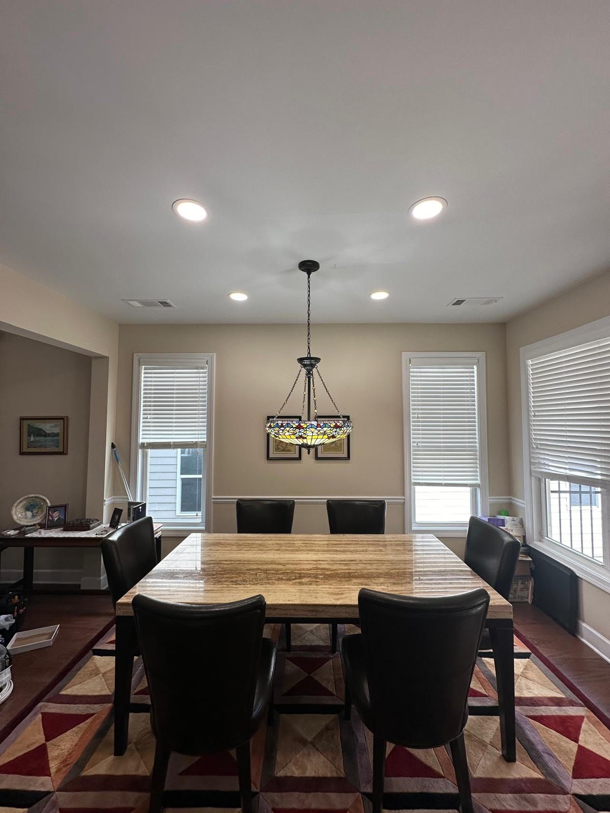 A dining room with a table and chairs and a chandelier hanging from the ceiling.