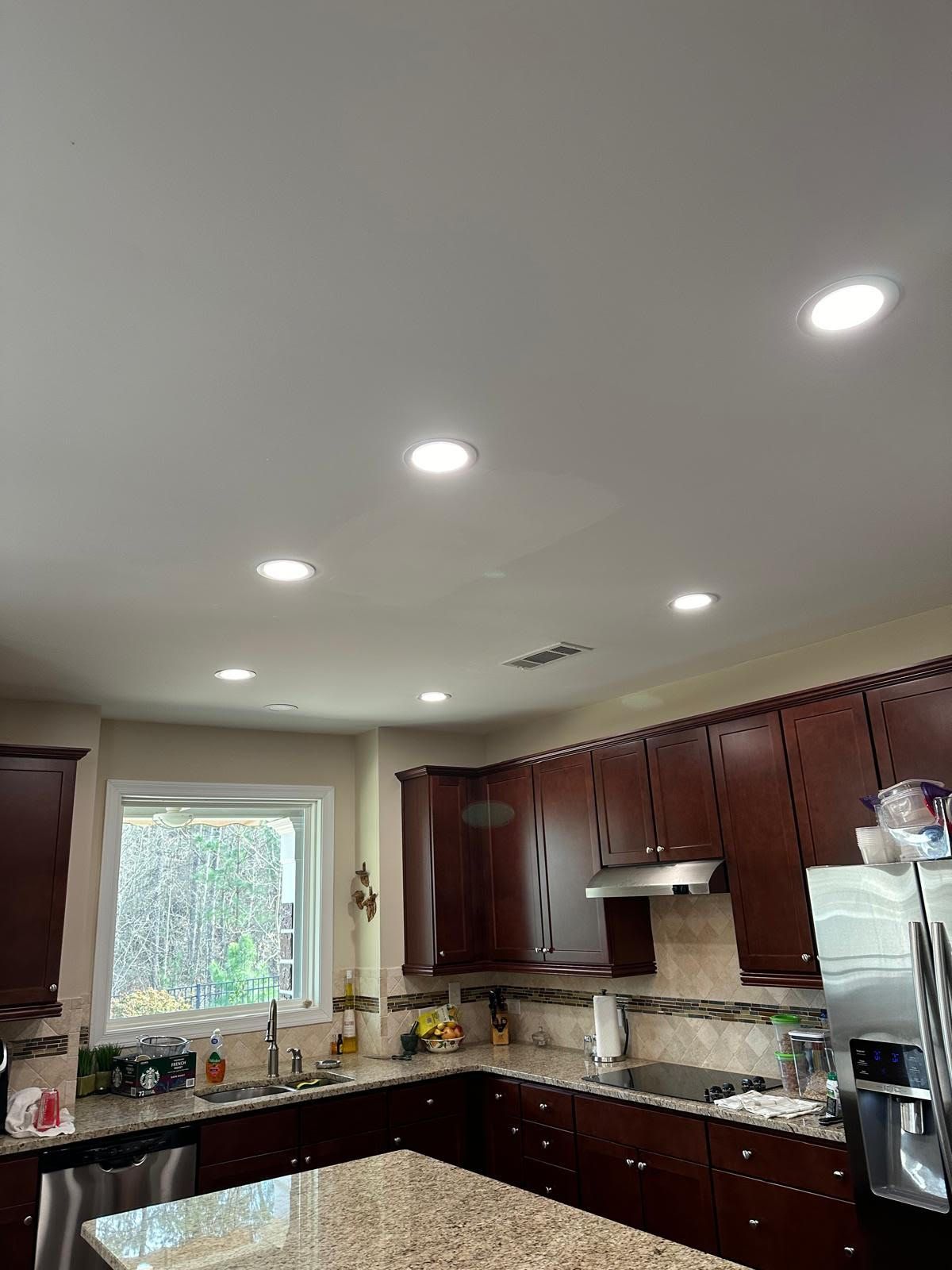 A kitchen with wooden cabinets , granite counter tops , stainless steel appliances , and a window.
