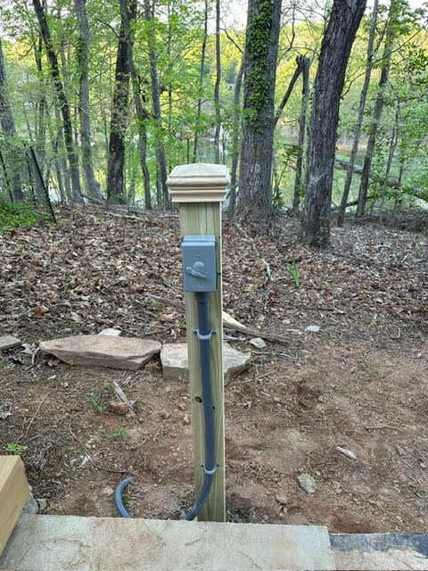A wooden post with a power outlet attached to it