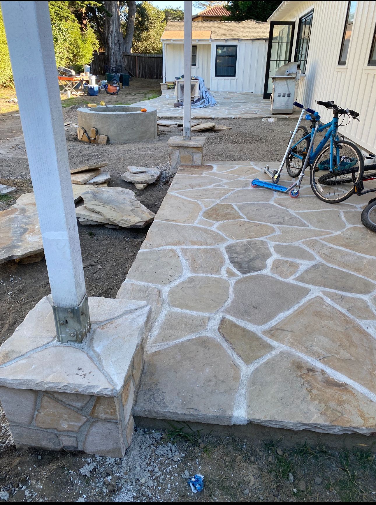 Flagstone patio with white grout, next to a house and bike.