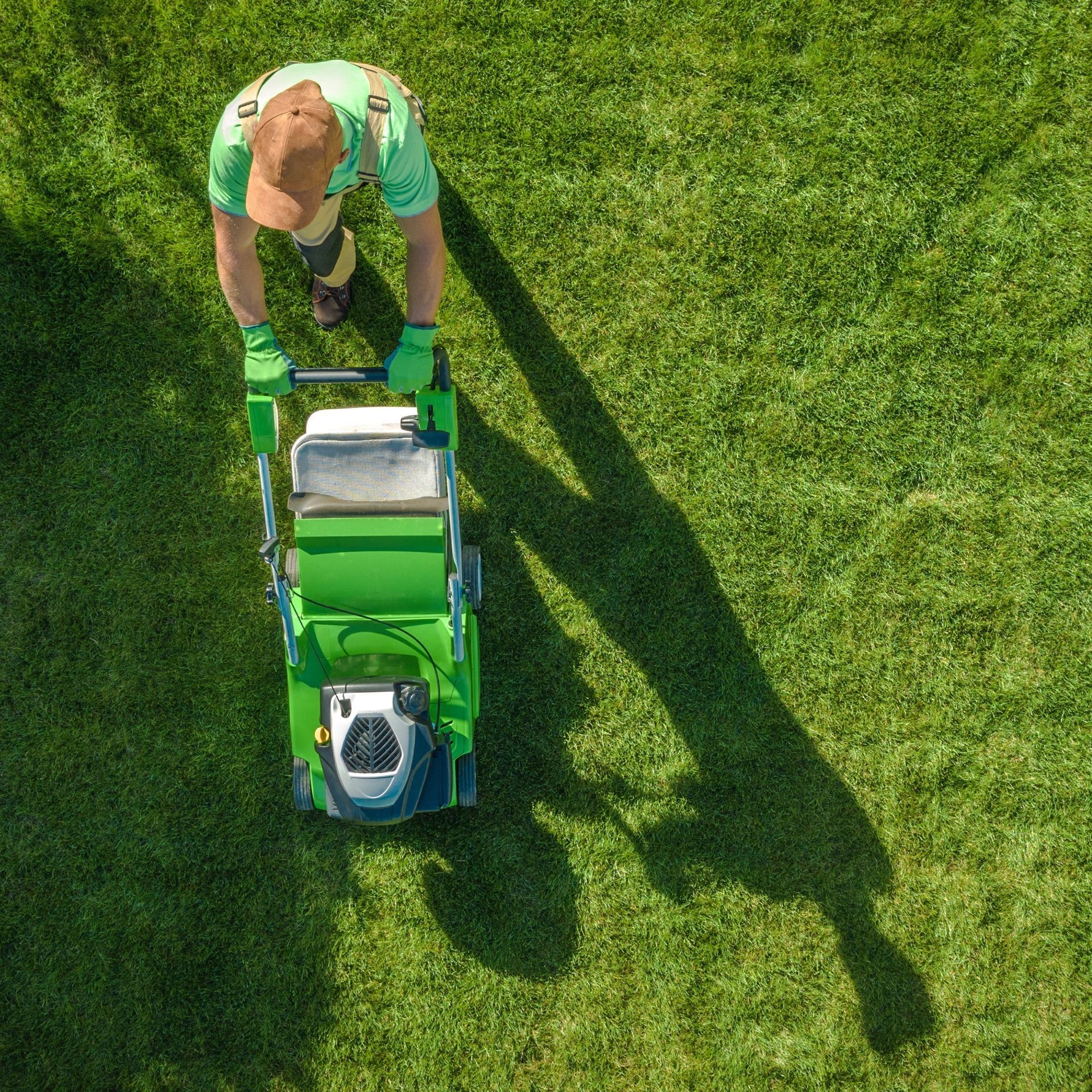 GREEN CANYON LANDSCAPING INC | A man is mowing a lush green lawn with a green lawn mower.