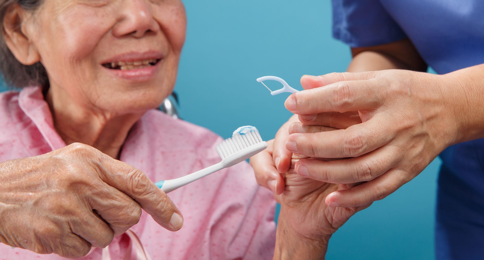 Person being assisted with dental hygiene; toothbrush and flosser present.