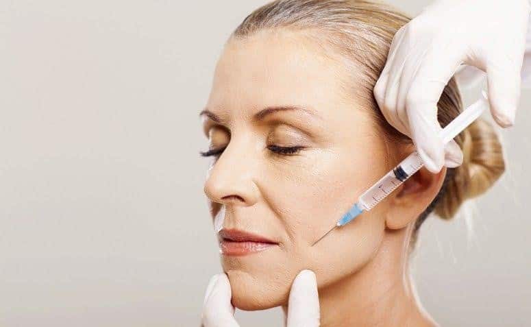Uma mulher está recebendo uma injeção de botox no rosto.