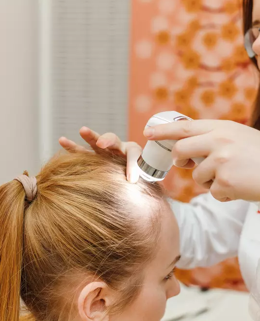 Uma mulher está examinando seu cabelo por um médico.
