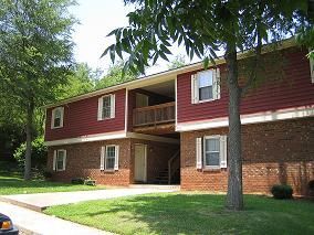 A red brick apartment building with a car parked in front of it.