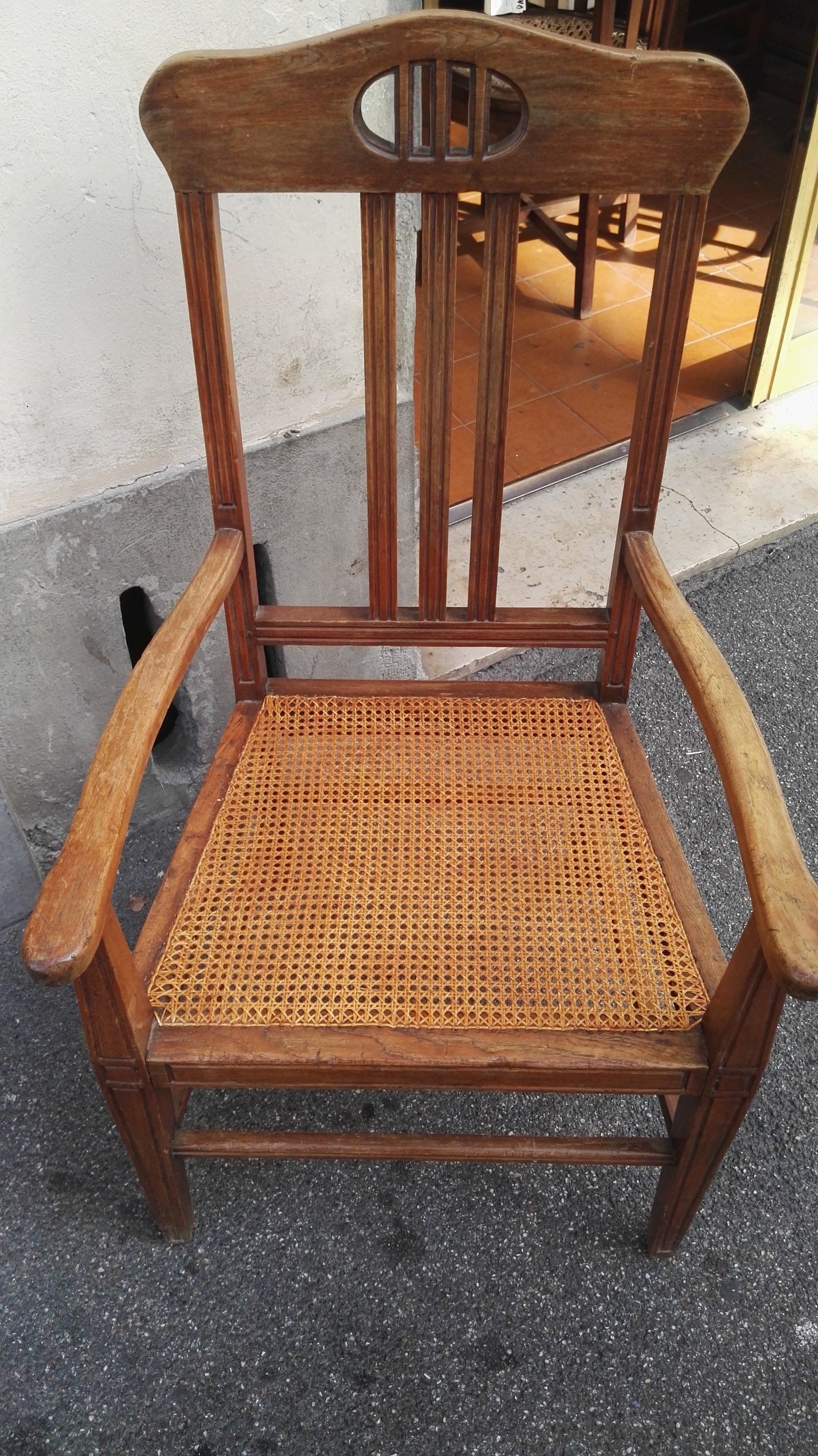 chaise avec poignées et dossier haut en bois et assise en paille tressée