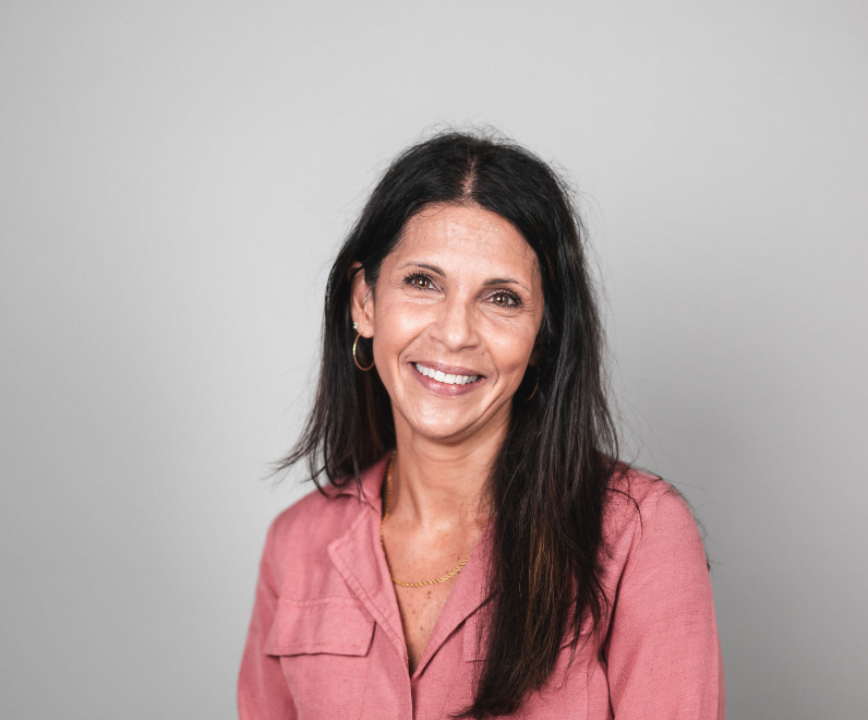A woman in a pink shirt is smiling for the camera.