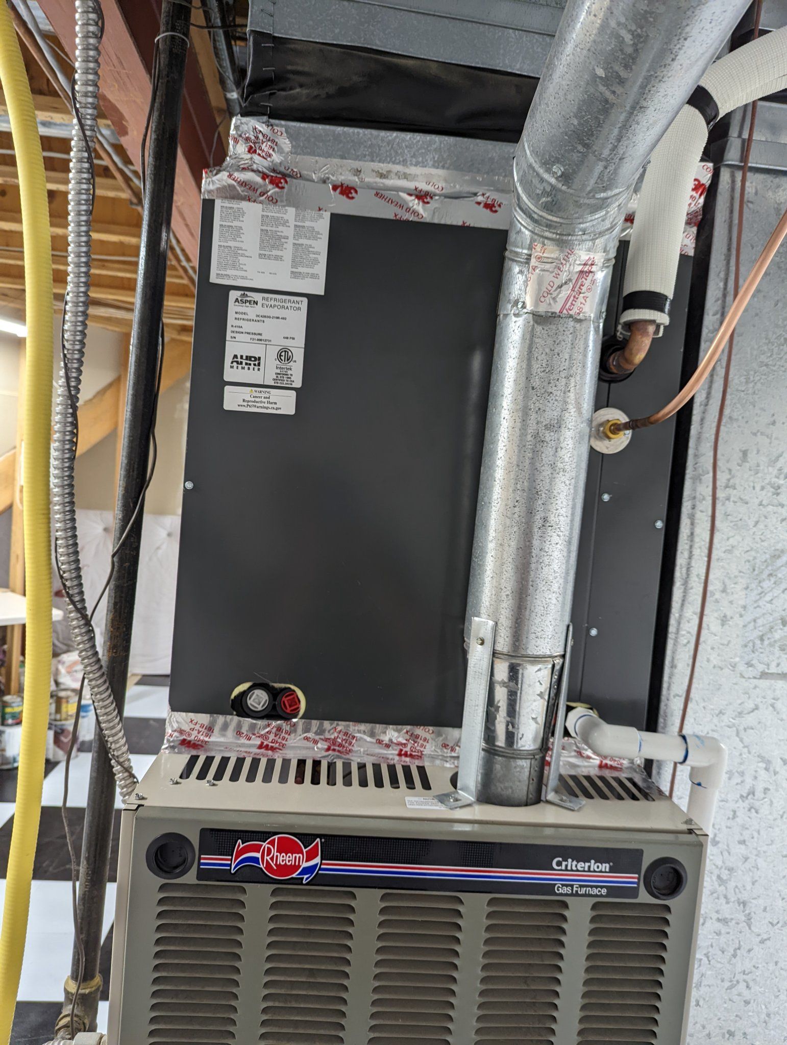 Furnace with ductwork in a basement. Silver and gray, vents at bottom, label on side.
