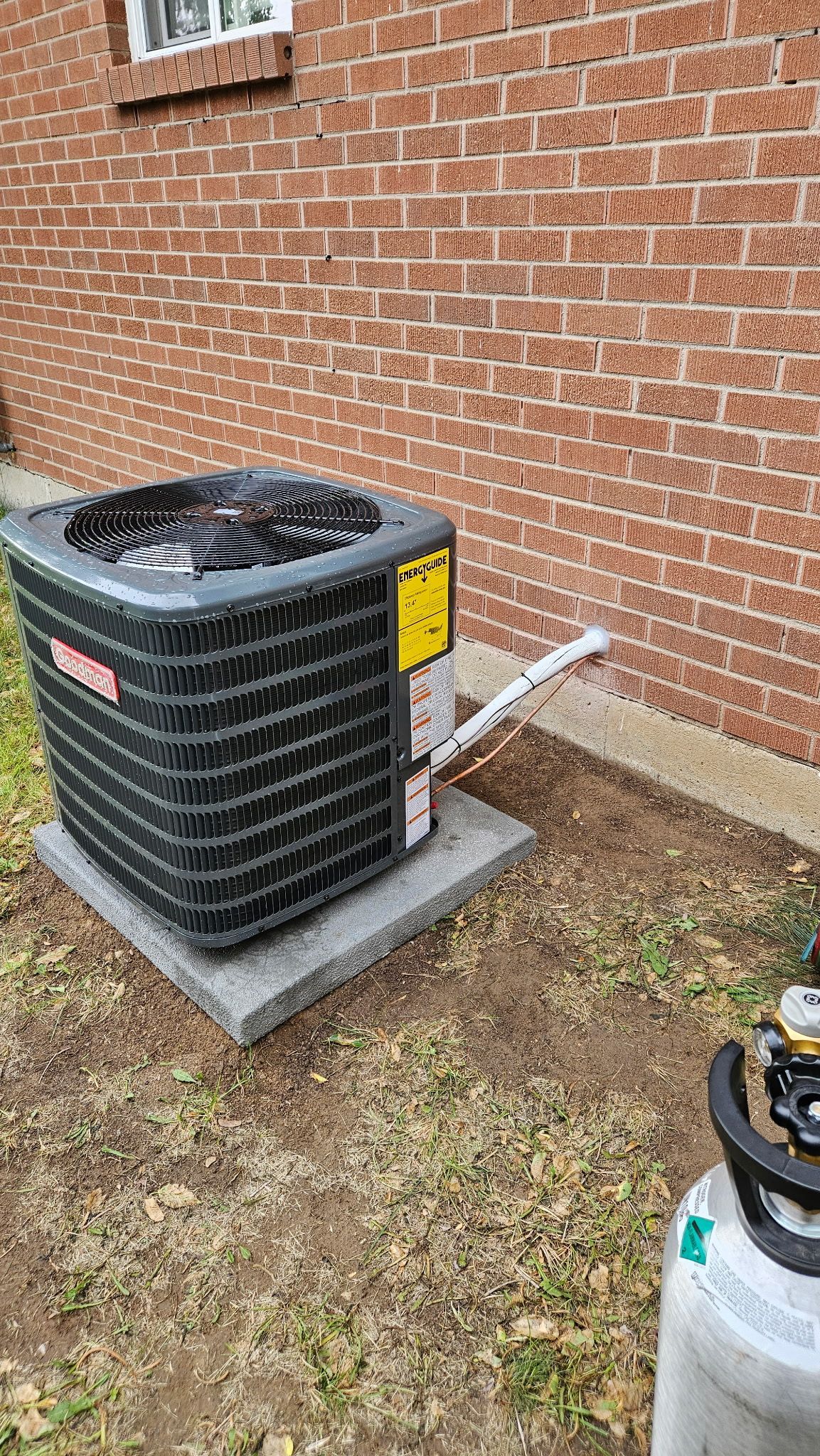 Air conditioning unit next to a brick building.