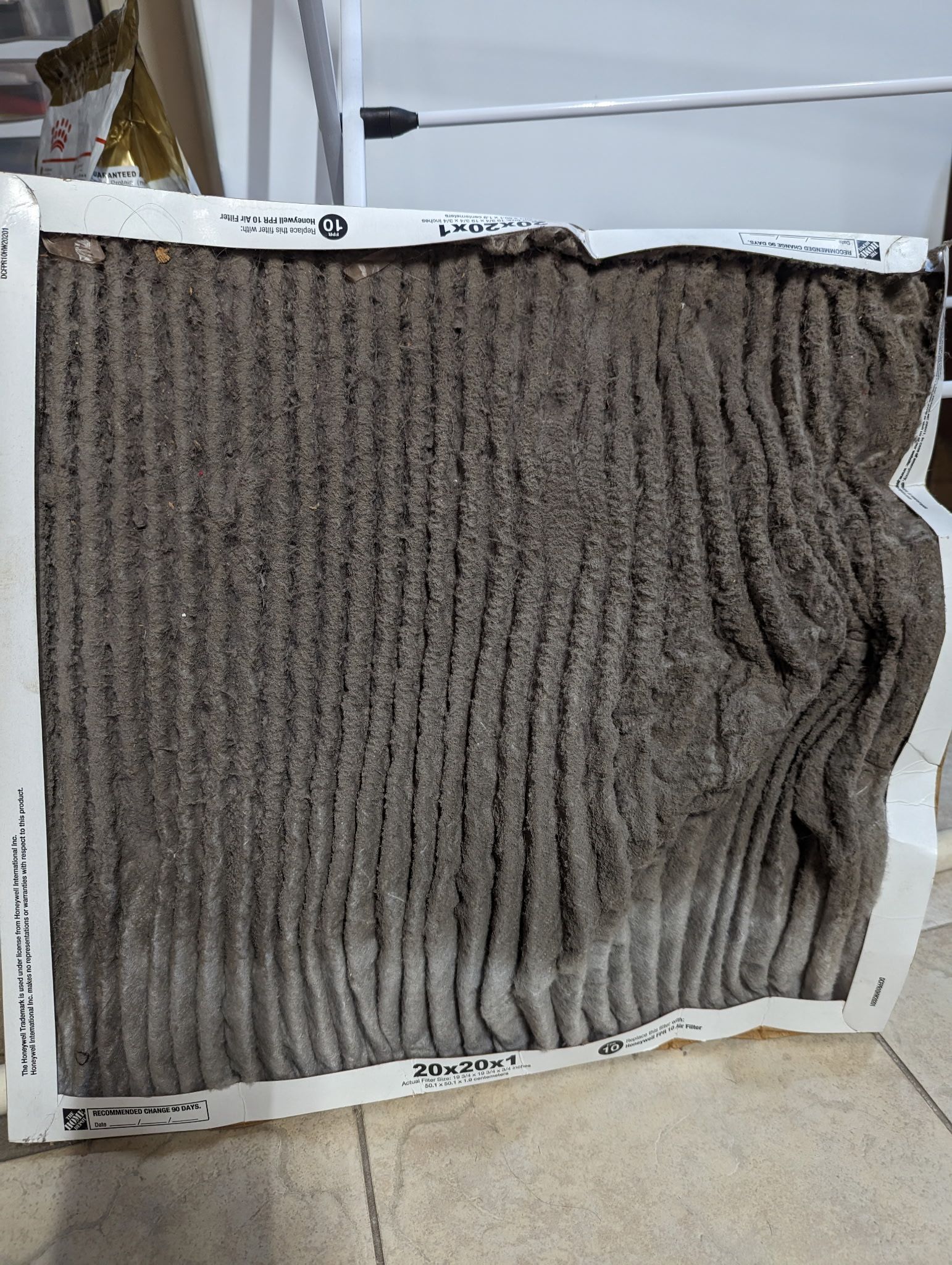 Dirty air filter, rectangular shape, with a pleated gray filter. White cardboard frame.