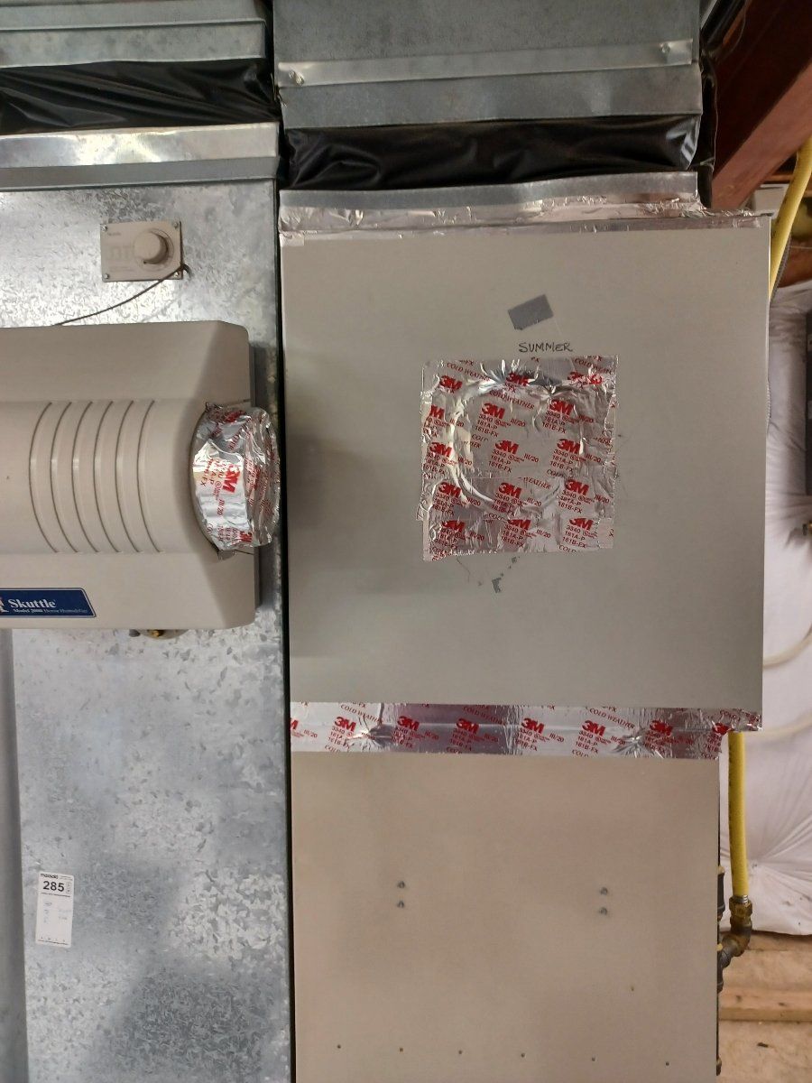 Metal furnace with attached humidifier, sealed with tape.