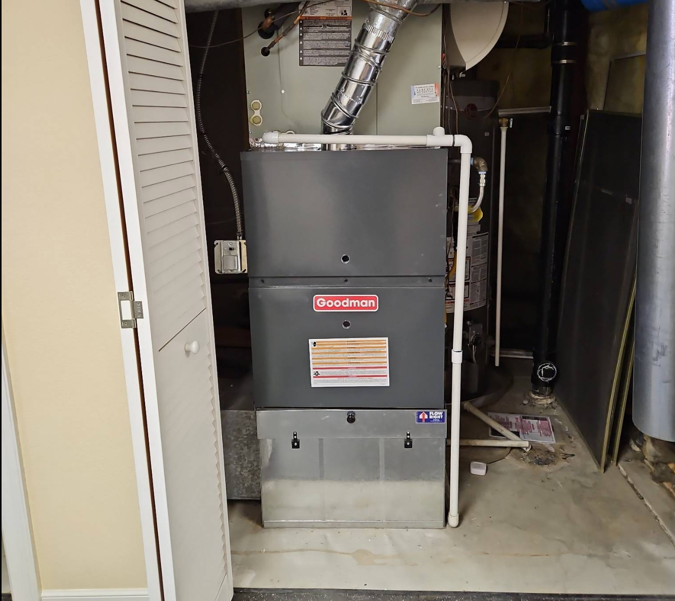 A white wall with a red fire alarm, a monitor, and a black control box.