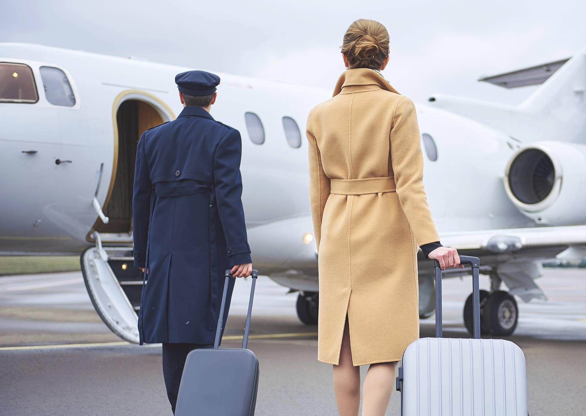 A man and a woman are walking towards a private jet.
