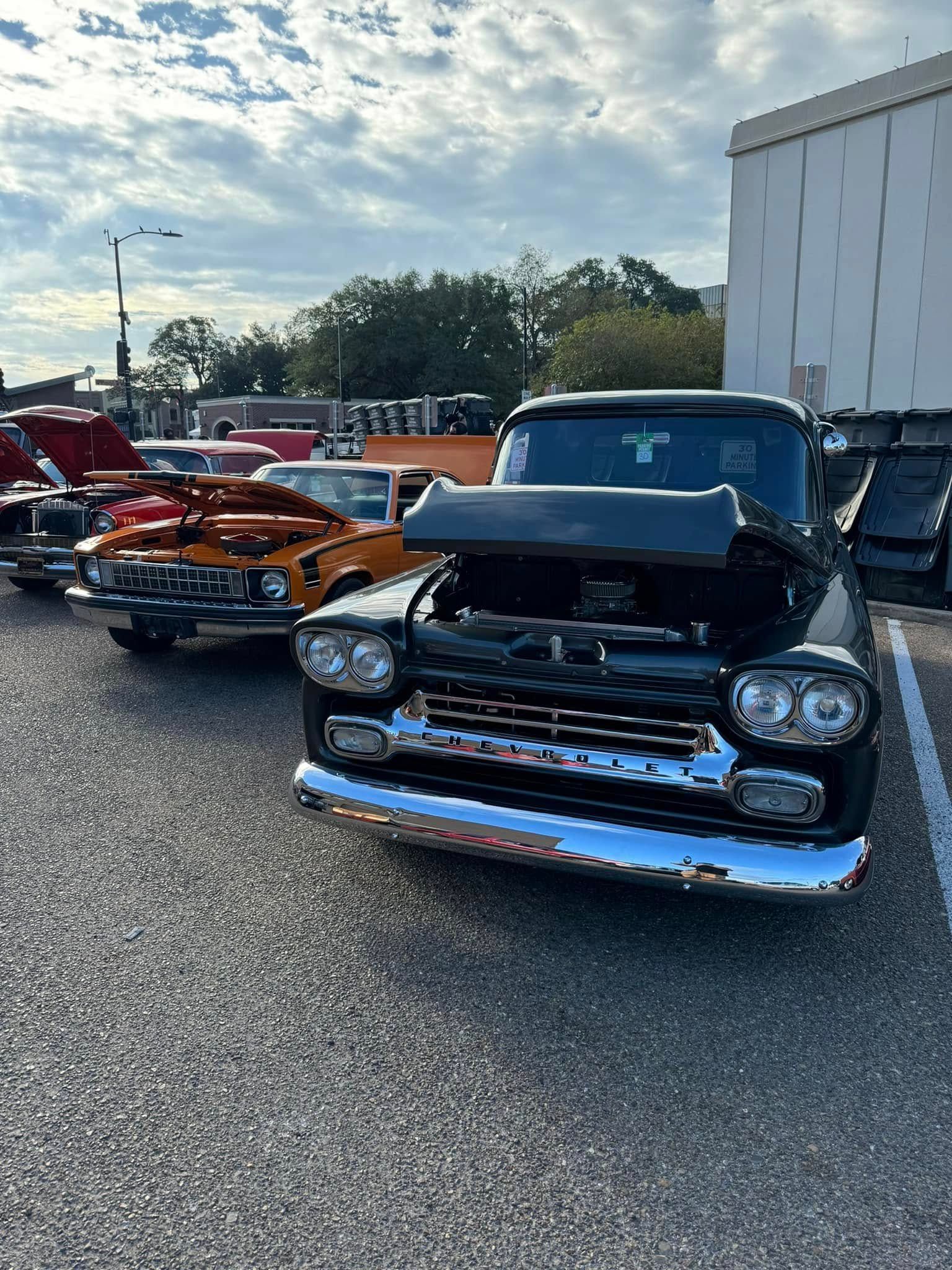 A row of old cars are parked in a parking lot.