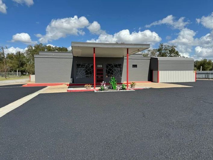 A small grey building with a red door and a red awning