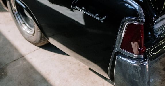 A black continental car is parked on the side of the road.