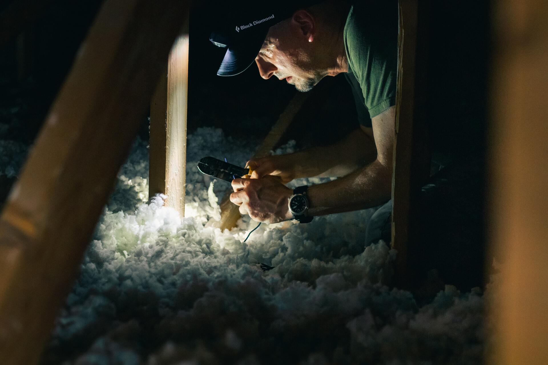 A man is working in an attic with a flashlight.