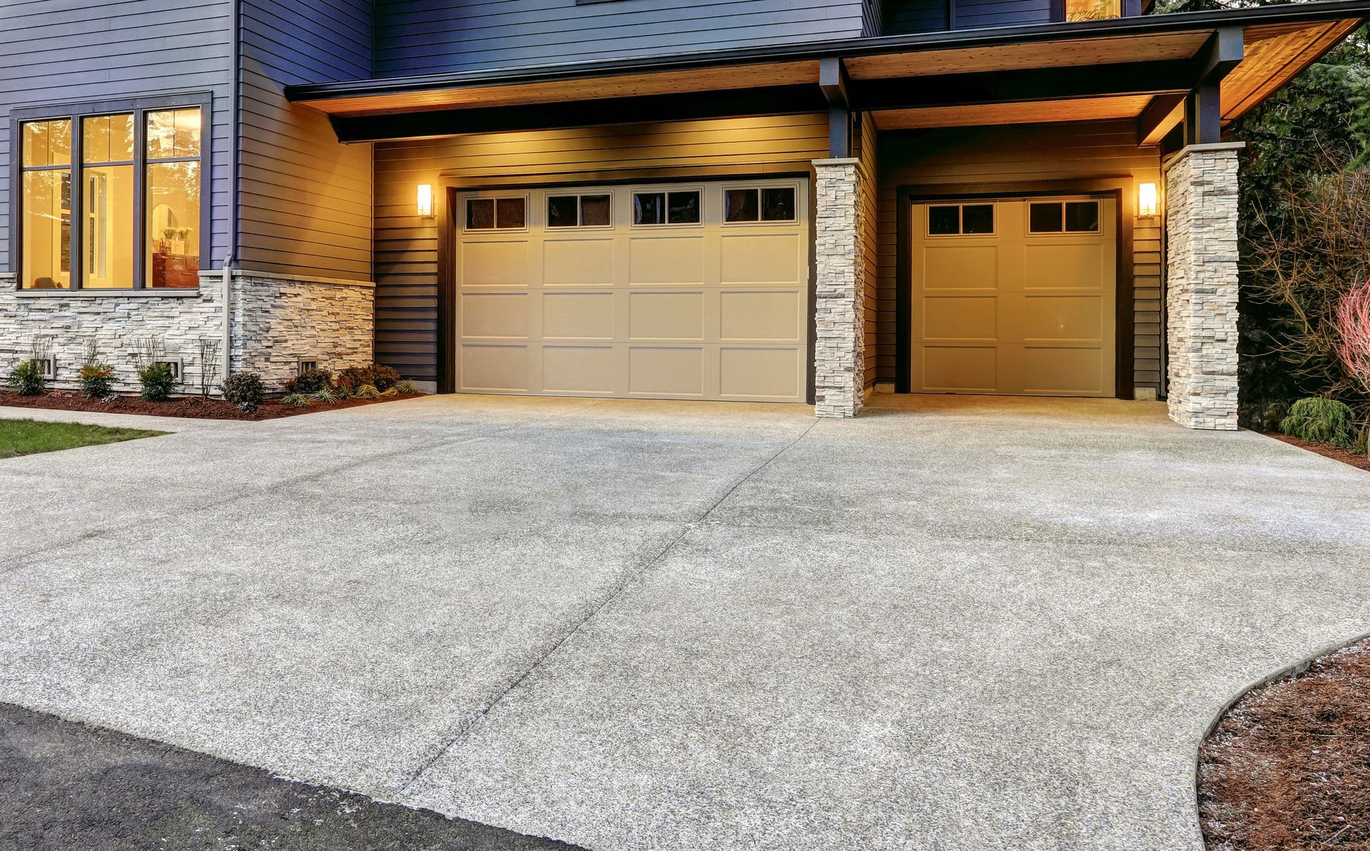 A large house with two garage doors and a concrete driveway.