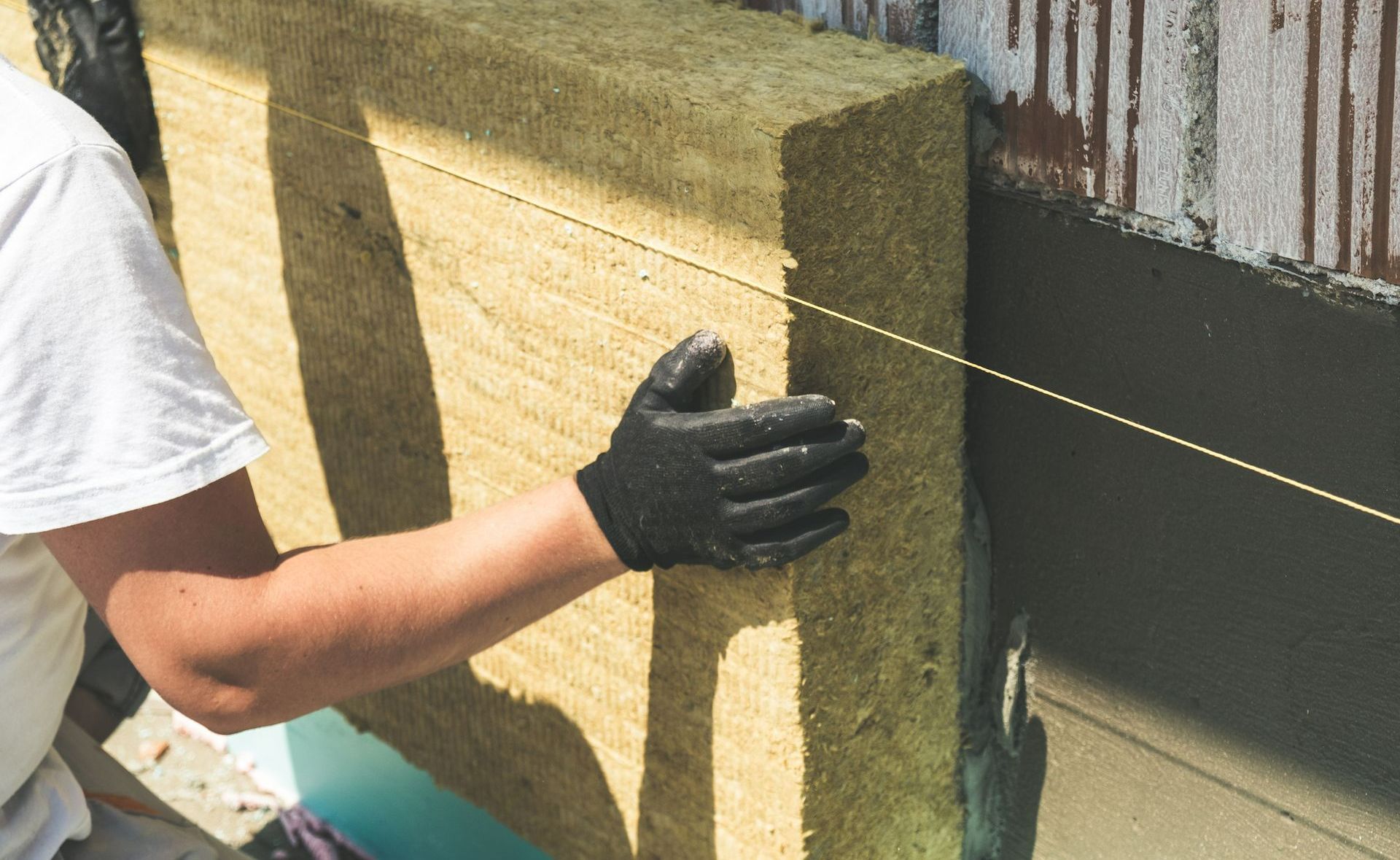 Un hombre con guantes negros mide un trozo de lana de roca.