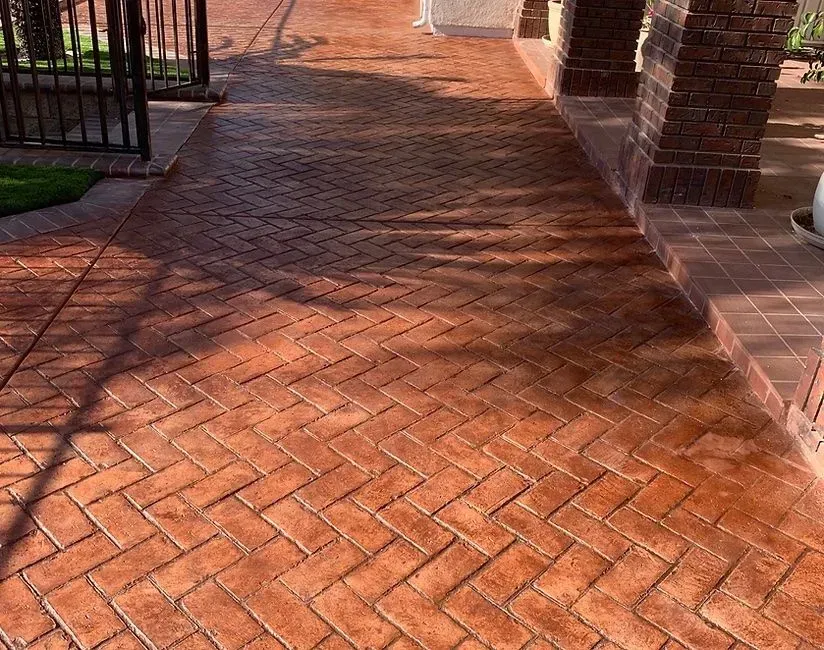 A brick walkway with a fence in the background.