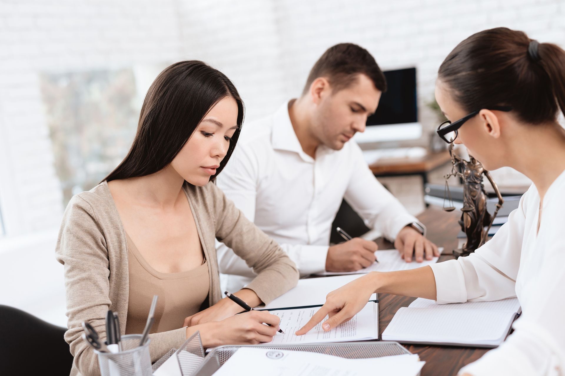 A couple is in the office of a female divorce lawyer, signing documents.