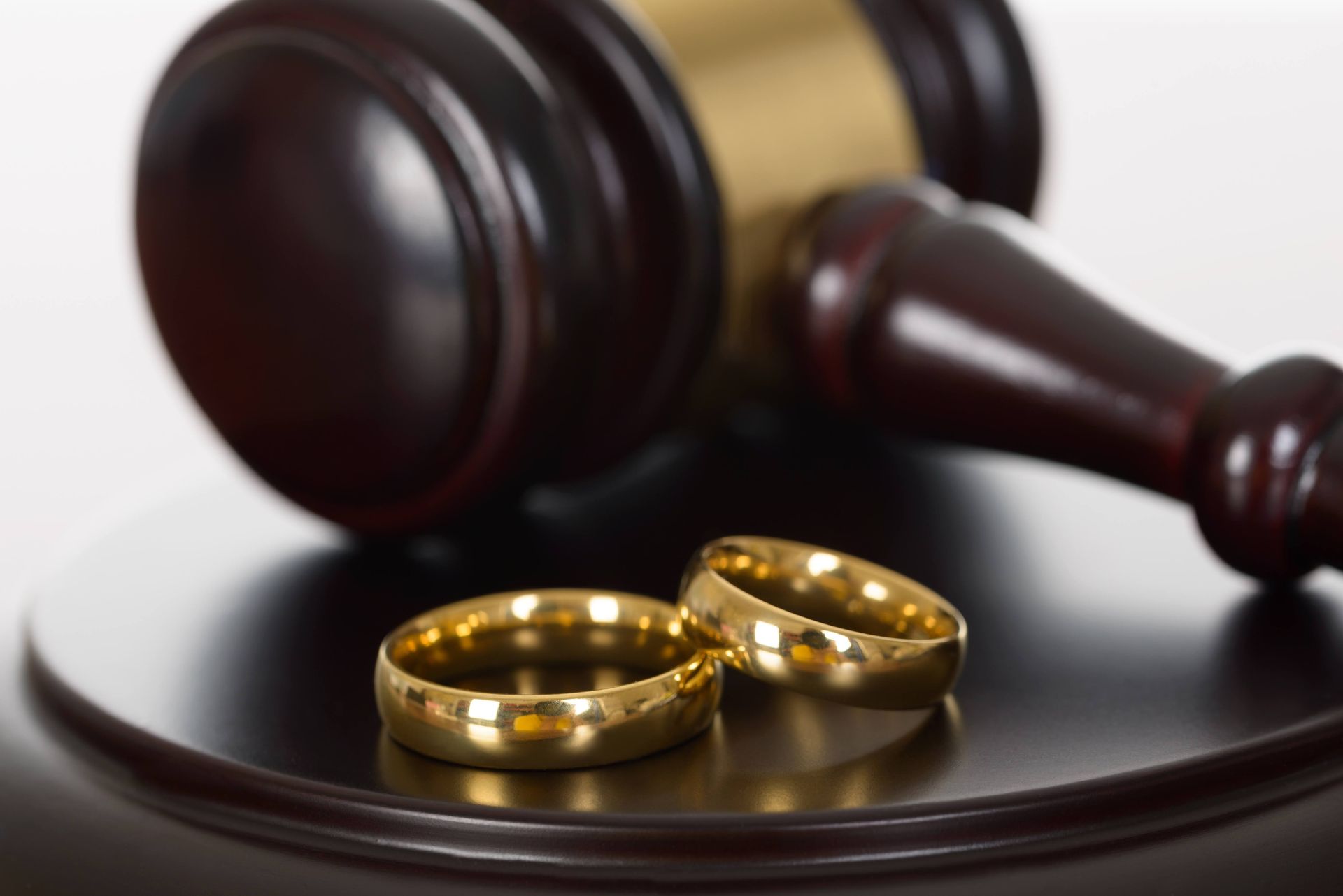 Wedding rings in front of a judge's gavel, symbolizing divorce proceedings.