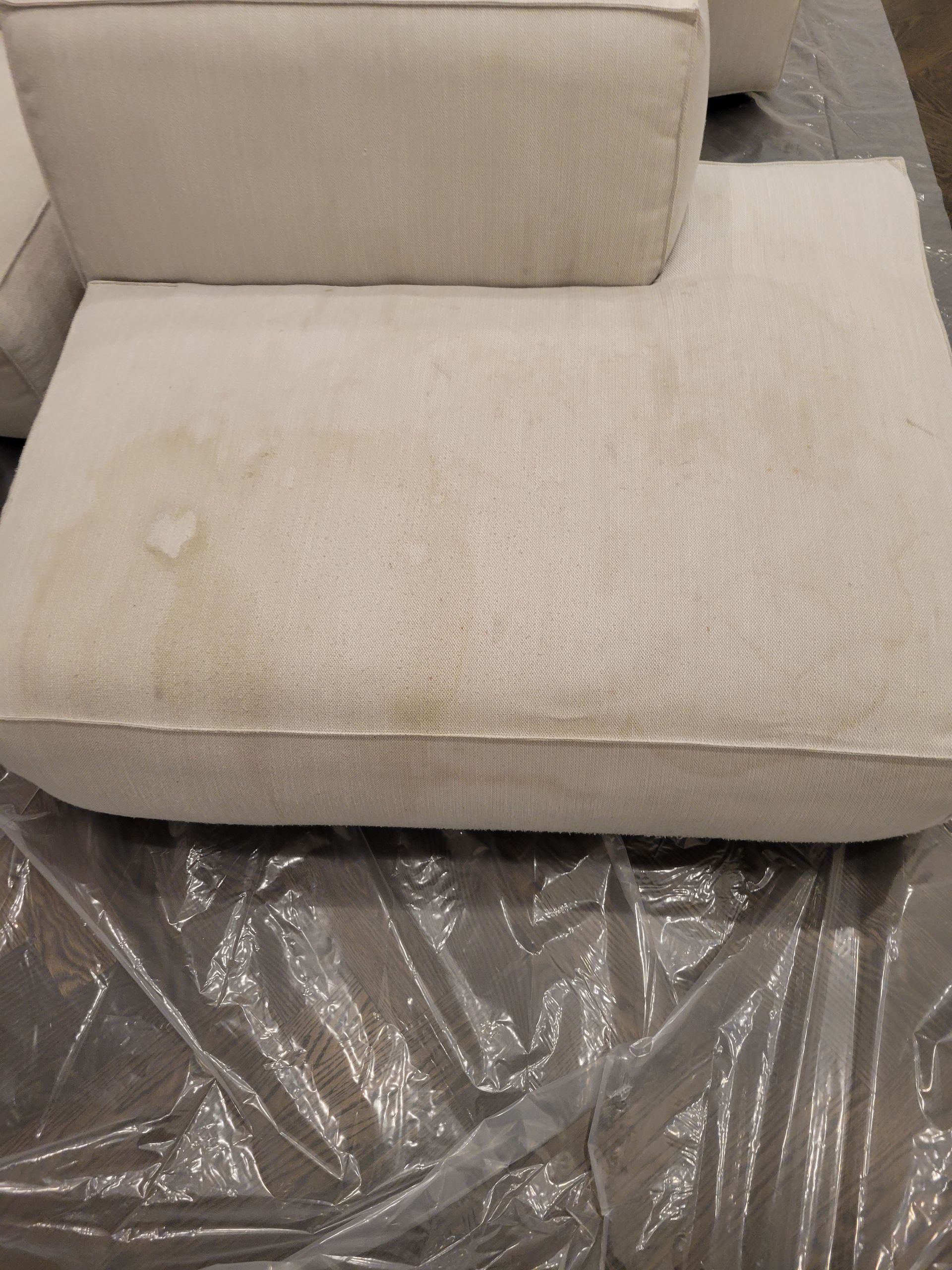 A white couch is sitting on top of a plastic sheet.