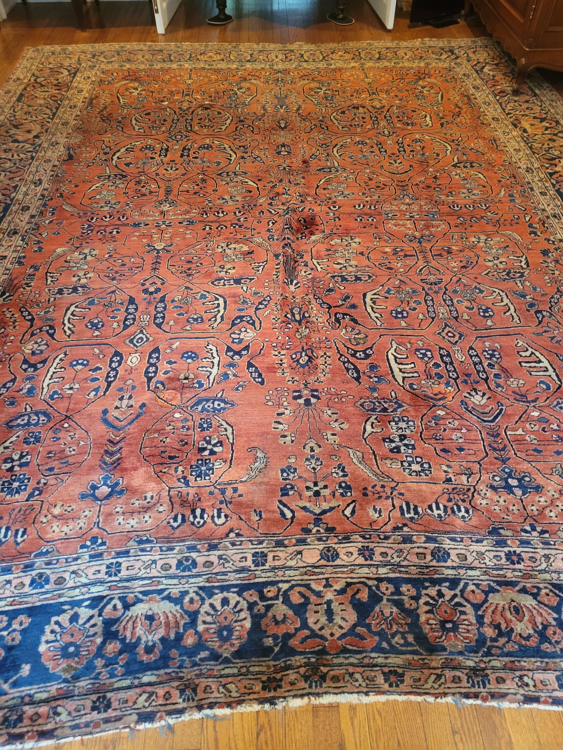 A large rug is sitting on a wooden floor in a living room.