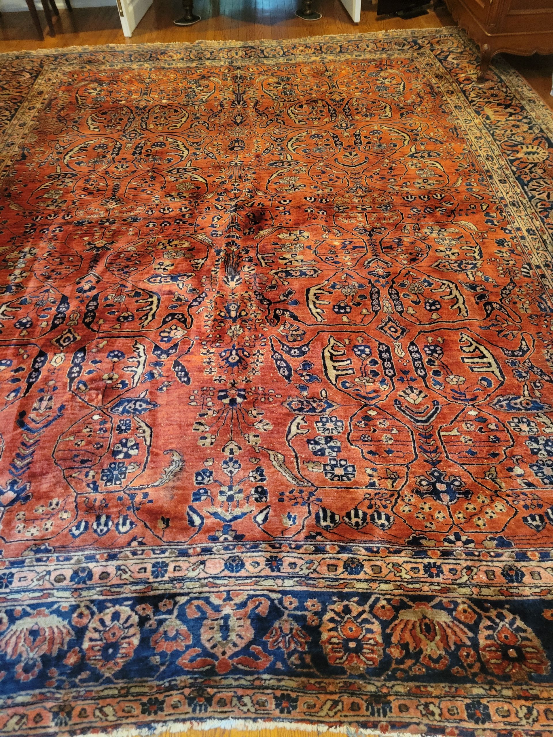 A large rug is sitting on a wooden floor in a living room.