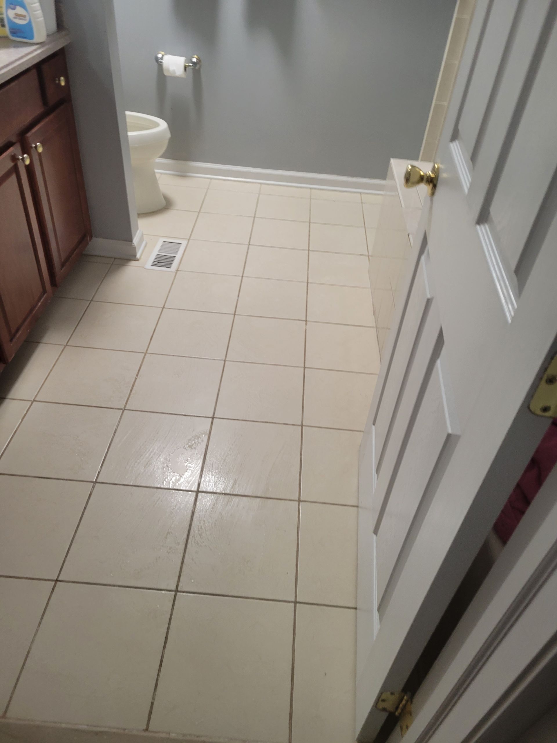 A bathroom with white tile floors and a toilet.