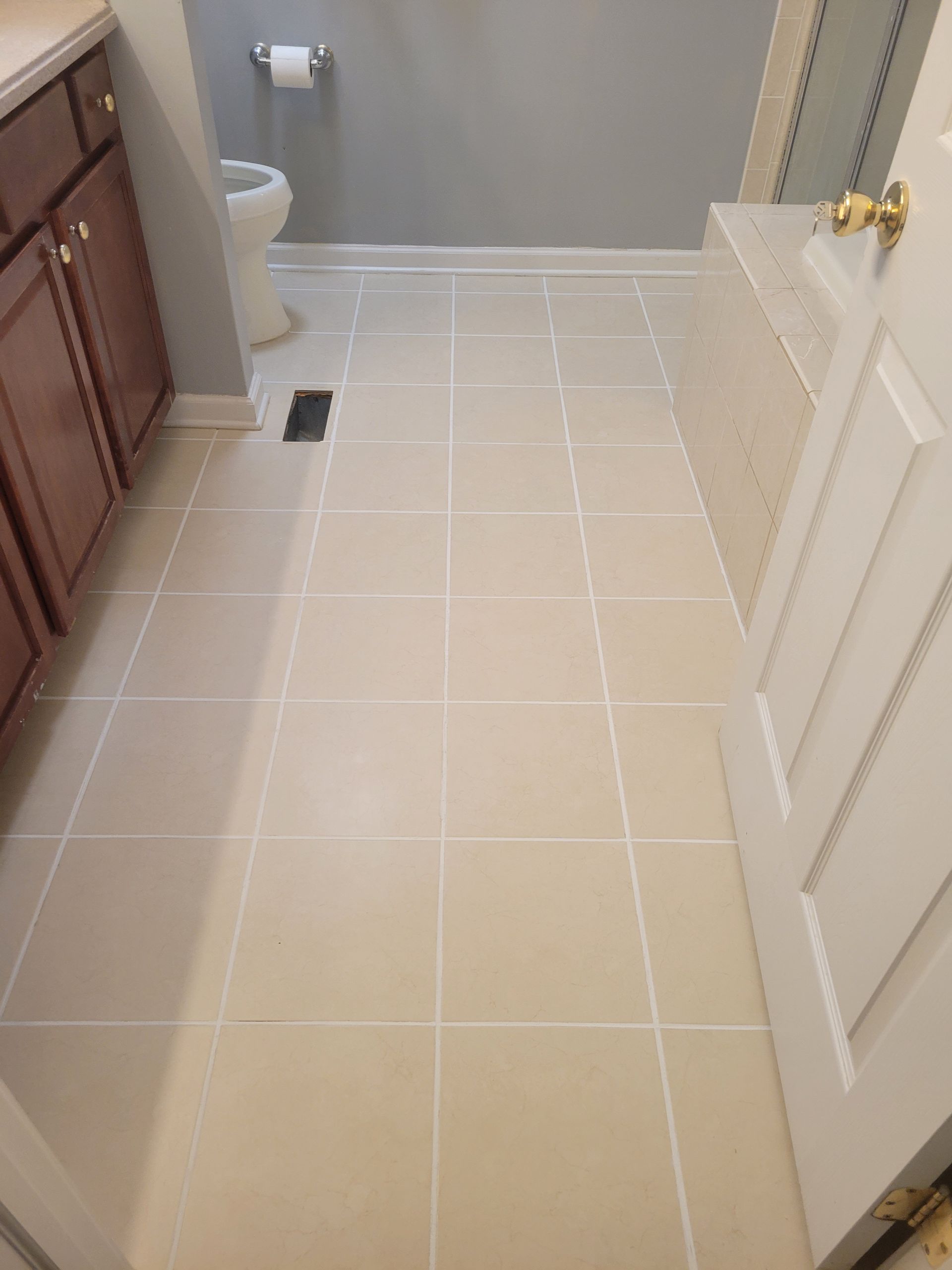 A bathroom with white tile floors and a toilet.